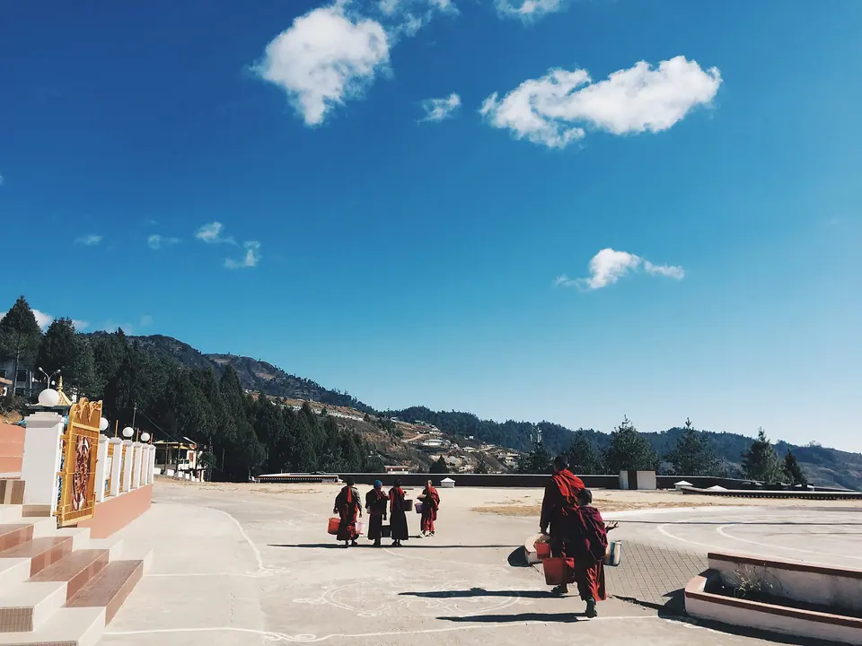 Monks crossing the terrace at Bomdila with forested ridges rolling away under a blue sky
