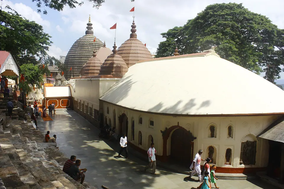 Kamakhya Temple's domed shikharas and long white hall above a stone-paved courtyard