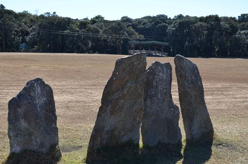 Tall standing stones of Khasi monoliths on a grassy clearing beside the Mawphlang sacred grove