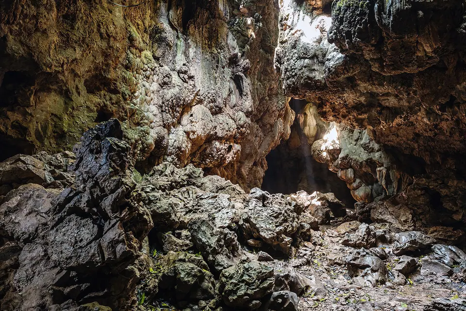 Lit chamber inside Mawsmai Cave with rough limestone walls and daylight filtering in