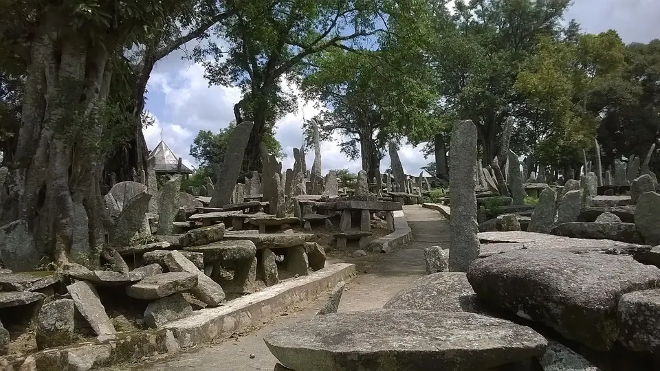 Stone tables and standing monoliths of the Nartiang memorial site shaded by old trees