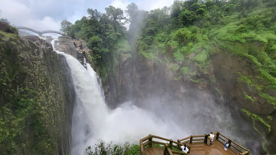 Weinia Falls at Nongkhnum thundering into a misty gorge beside a wooden viewing platform, West Khasi Hills