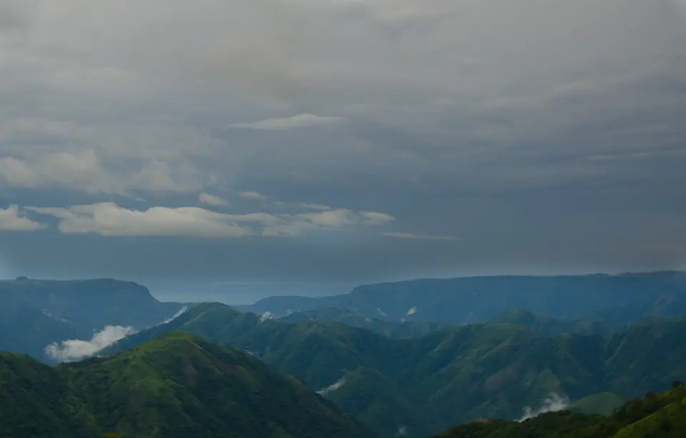 Layered green ridges and deep valleys under grey monsoon skies around Sohra, Meghalaya