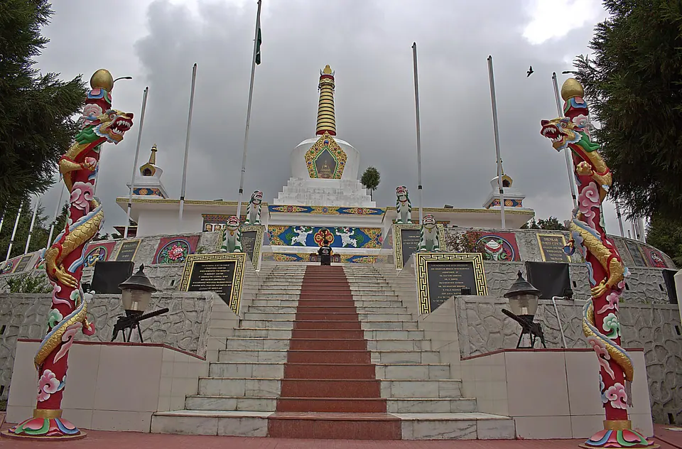 Steps rising to the white stupa of the Tawang War Memorial, flanked by painted dragon pillars