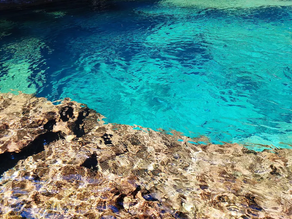 Clear turquoise water over a pitted rock shelf in the plunge pool at Wei Sawdong