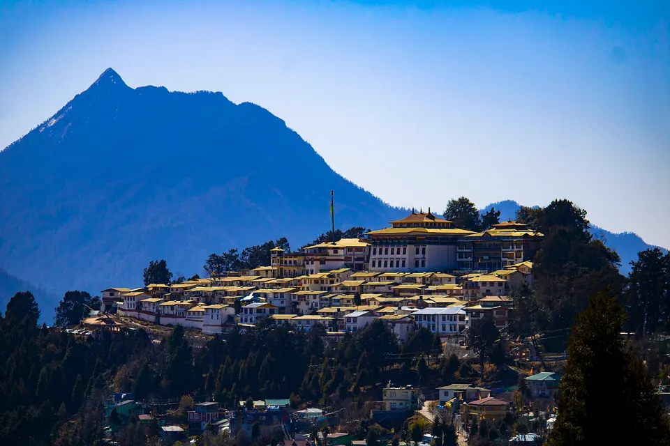 Tawang Monastery seen from a distance, its gold roofs strung along a forested ridge