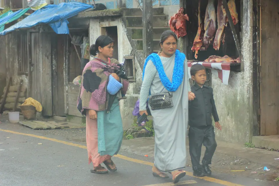A Khasi family in shawls walking past market stalls on a Shillong street