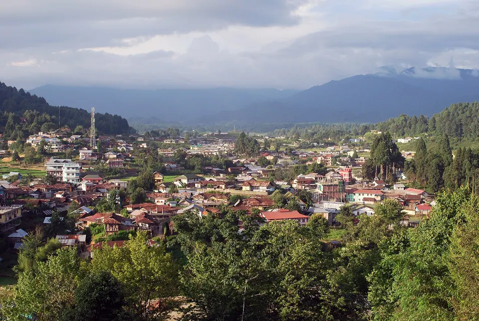The red and grey roofs of Ziro town filling the valley under a cloudy sky